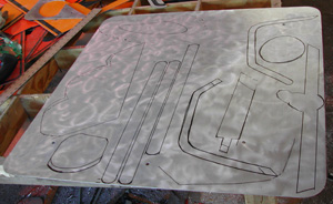 Back of a road sign with a polished silbver surface and some traced shapes ready to be cut out
